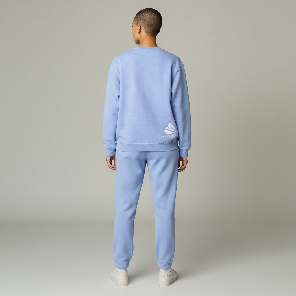 Person wearing a light blue tracksuit with a logo on a plain background