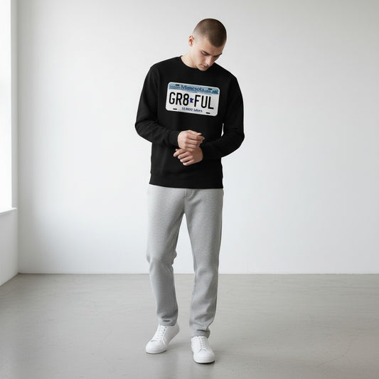 Person wearing a black long sleeve tee with a MN license plate design, standing in a minimalistic room.