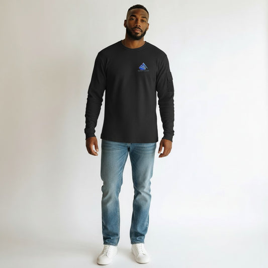 Man wearing a black long-sleeve shirt with a logo and blue jeans on a white background