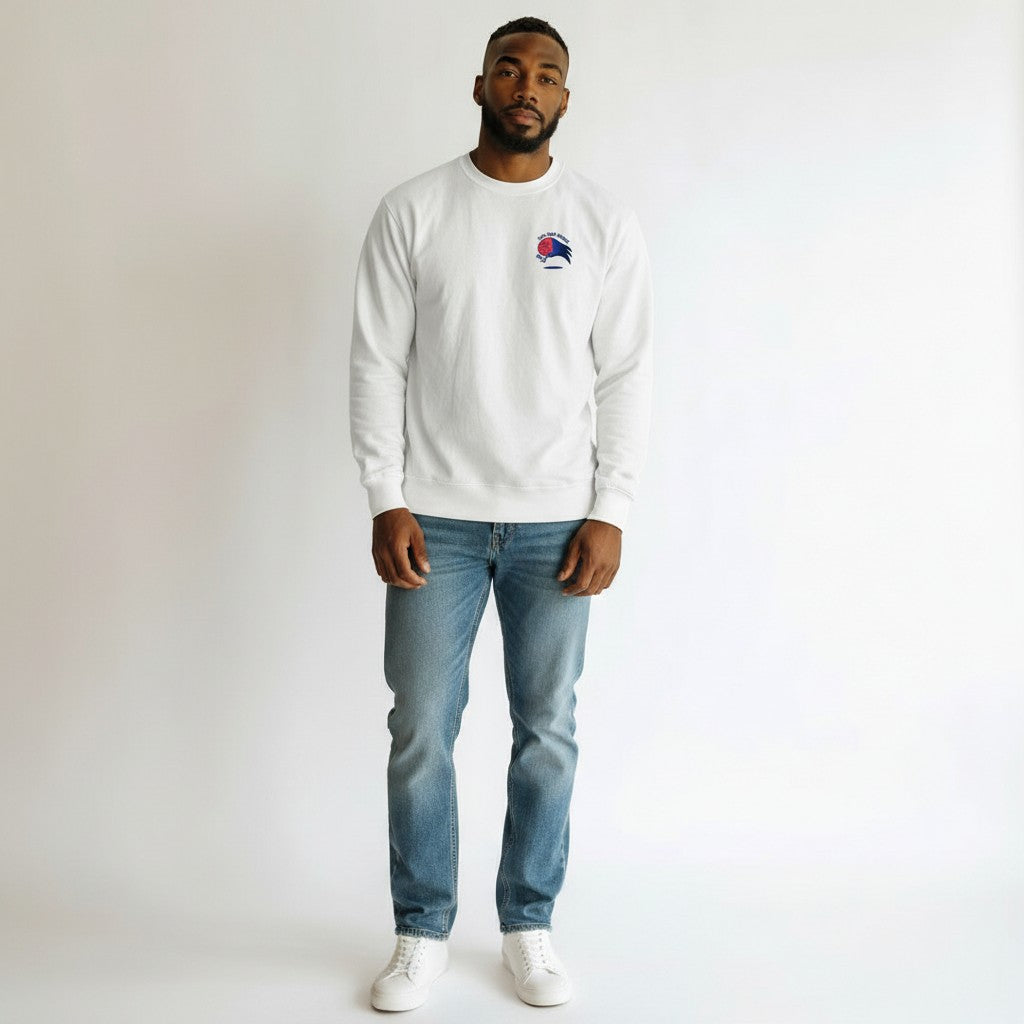 Man wearing a white sweatshirt with a logo and blue jeans on a plain background
