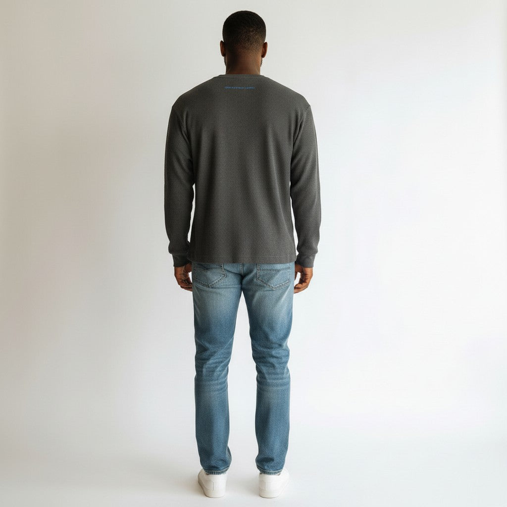 Man wearing a gray long-sleeve shirt and blue jeans on a white background