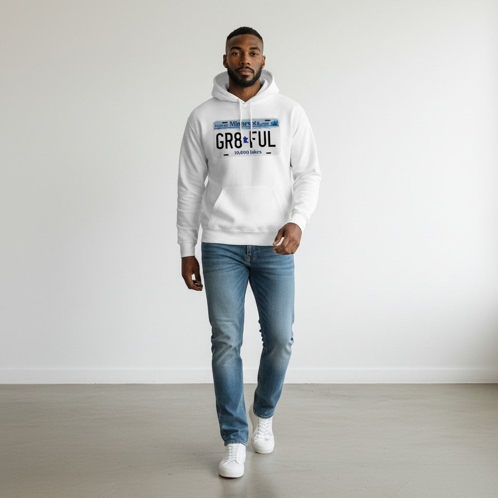 Man wearing a white hoodie with text and blue jeans standing against a plain background