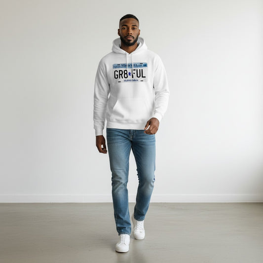 Man wearing a white hoodie with text and blue jeans standing against a plain background