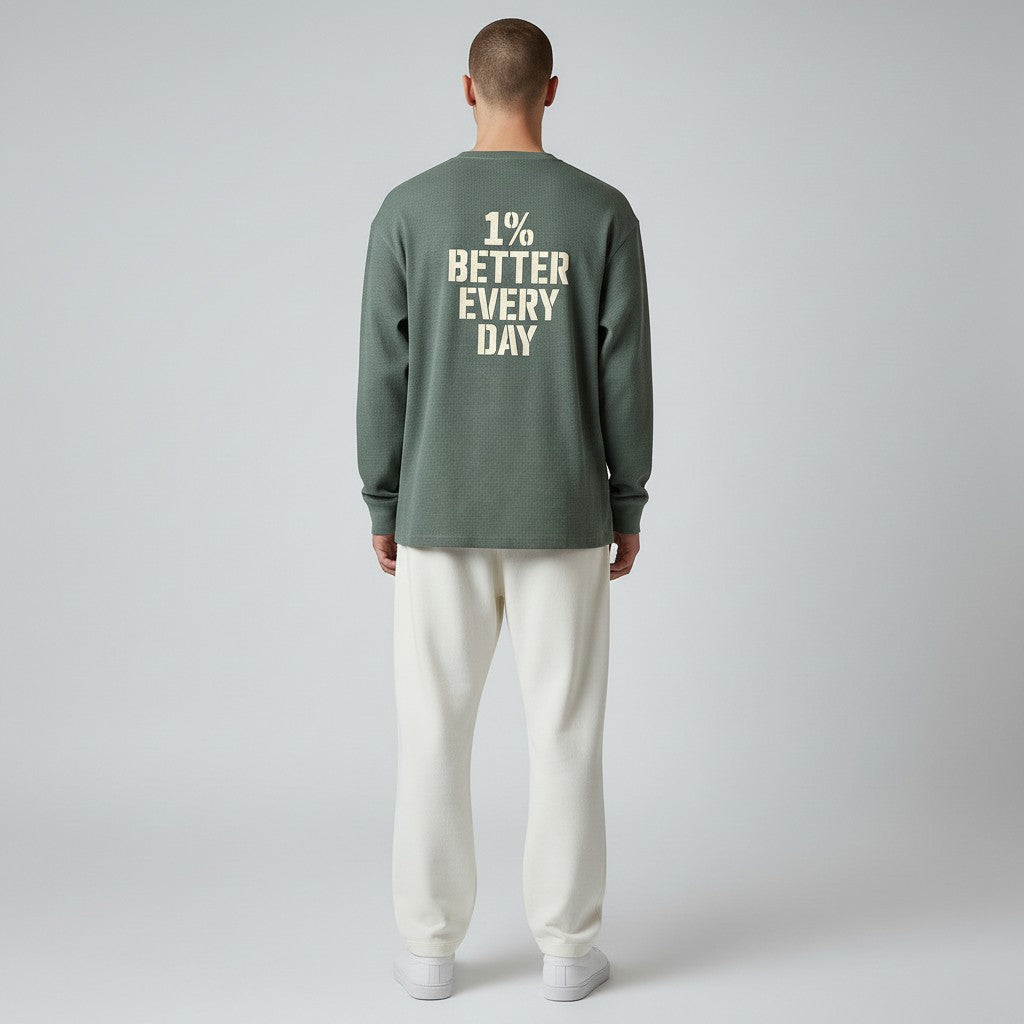 Person wearing a green long-sleeve shirt with '1% Better Every Day' text on the back, standing against a plain background.