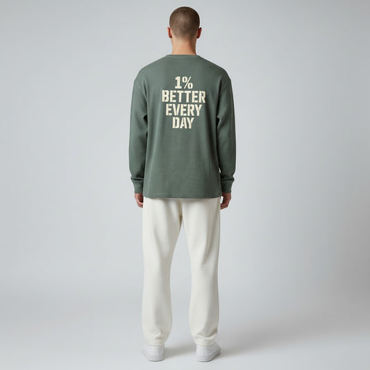 Person wearing a green long-sleeve shirt with '1% Better Every Day' text on the back, standing against a plain background.